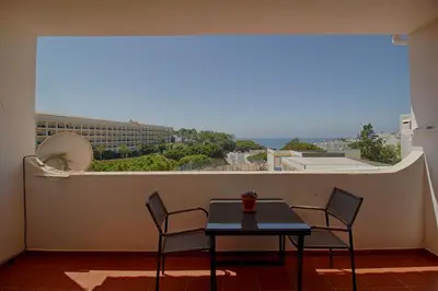 a table and chairs on a balcony with a view at Apartamento Olhos D'Água VistaBella in Olhos de Água
