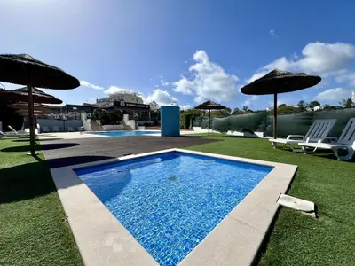 a swimming pool with two chairs and umbrellas at Albufeira Modern 2 With Pool by Homing in Albufeira