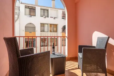 a balcony with chairs and a table and a building at Quarteira Beach - 2 D by HelloVacations in Loulé