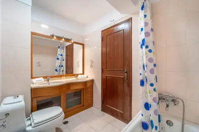 a bathroom with a toilet and a sink and a mirror at Quarteira Beach - 2 D by HelloVacations in Loulé