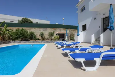 a row of blue and white chairs next to a swimming pool at Apart Quinta dos Martins - swimming pool - BY BEDZY in Albufeira