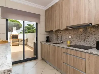 a kitchen with wooden cabinets and a view of a patio at Magnólia O House by Stay ici Algarve Holiday Rental in Albufeira
