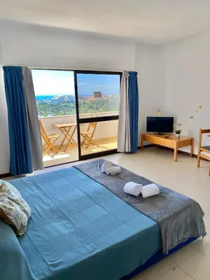 a bedroom with a blue bed and a large window at Endless Summer in Albufeira