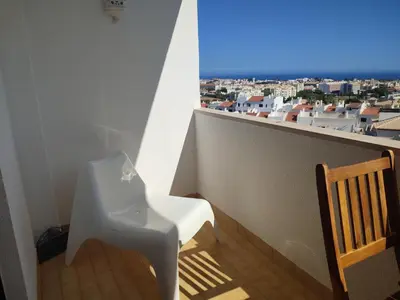 a balcony with a chair and a view of a city at Endless Summer in Albufeira