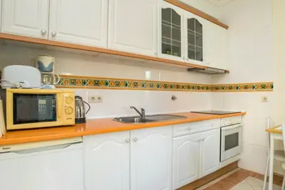 a kitchen with white cabinets and towels on a blue rug at Apartamento Studio Anastacio in Albufeira