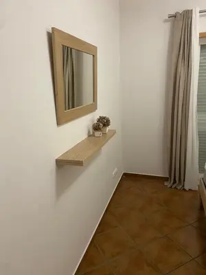 a room with a mirror and a shelf on a wall at Parra Home Holidays - Close to Galé Beach in Guia