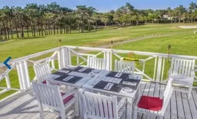 a table and chairs on a deck with a golf course at Quinta do Lago Golf, Sea & Sun in Quinta do Lago