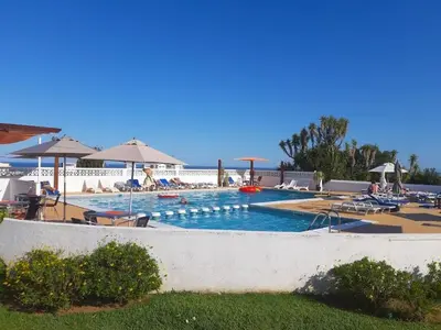 a swimming pool with people laying on chairs and umbrellas at One Bedroom Apartment Marina View in Albufeira