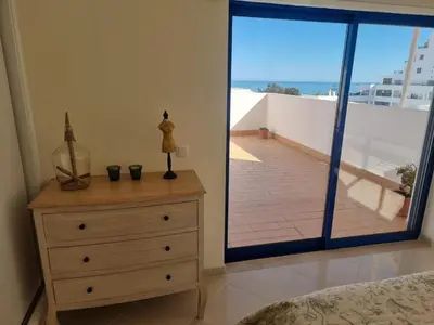 a bedroom with a dresser and a view of a balcony at Pérola do Atlântico By the Sea in Quarteira