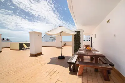 a patio with a table and an umbrella on a roof at Pérola do Atlântico By the Sea in Quarteira