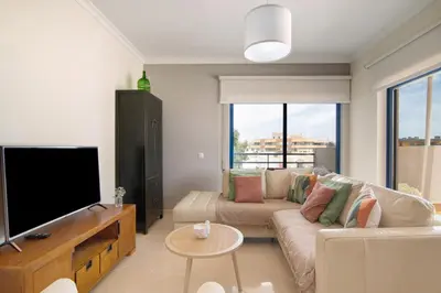 a living room with a couch and a flat screen tv at Pérola do Atlântico By the Sea in Quarteira