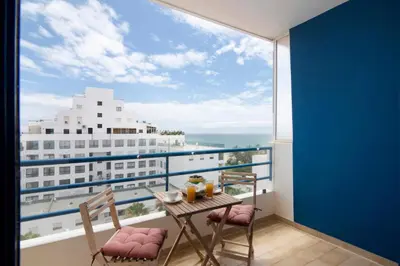 a balcony with a table and chairs and a large window at Pérola do Atlântico By the Sea in Quarteira