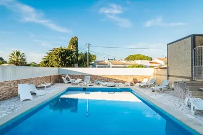 a swimming pool with blue water and white chairs around it at T1 Anastacio in Albufeira