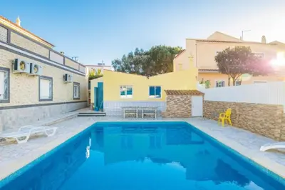 a swimming pool in front of a house at T1 Anastacio in Albufeira