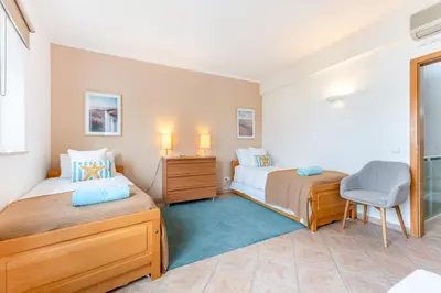 a bedroom with two beds and a chair at Casa Perola - Vale do Garrão in Almancil
