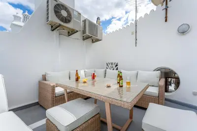 a patio with a table and chairs and a fan at Casa Perola - Vale do Garrão in Almancil