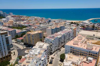an aerial view of a city with buildings and the ocean at 1BR Infante Flat in Quarteira by LovelyStay in Quarteira