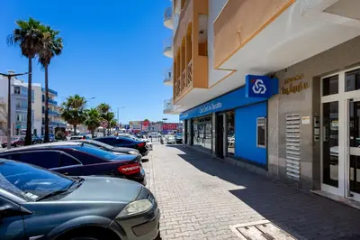 a row of parked cars parked in front of a building at 1BR Infante Flat in Quarteira by LovelyStay in Quarteira