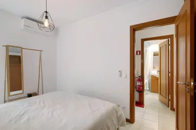 a bedroom with a white bed and a open door at Ae Flat Falesia in Albufeira