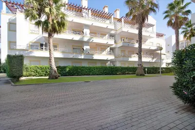 a large white building with palm trees in front of it at Ae Flat Falesia in Albufeira