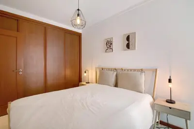 a bedroom with a white bed and wooden cabinets at Ae Flat Falesia in Albufeira