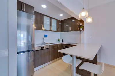 a kitchen with wooden cabinets and a stainless steel refrigerator at AL - Oceano T2 Frente Mar Quarteira in Quarteira