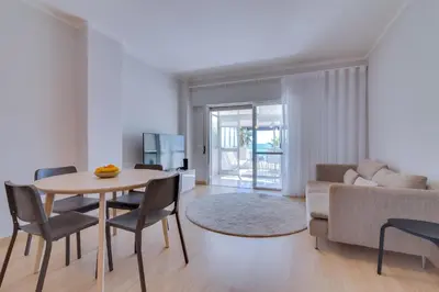 a living room with a table and chairs and a couch at AL - Oceano T2 Frente Mar Quarteira in Quarteira
