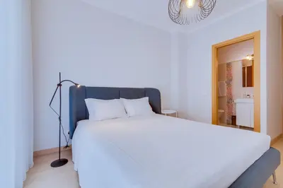 a bedroom with a white bed with a blue headboard at AL - Oceano T2 Frente Mar Quarteira in Quarteira