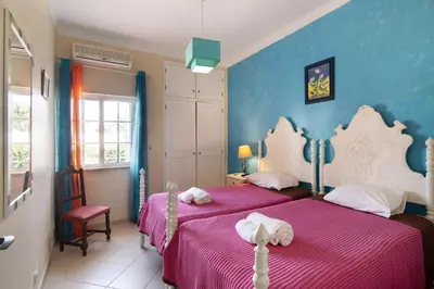 a bedroom with two beds with pink and blue walls at Villa Paraíso in Olhos de Água