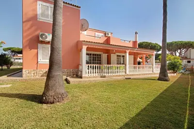 a pink house with two palm trees in the yard at Villa Paraíso in Olhos de Água