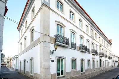 a white building with windows and balconies on a street at Beach Waves Apartment in Faro