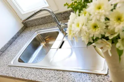 a kitchen sink with a vase of flowers next to it at Coast Guard Apartment in Faro