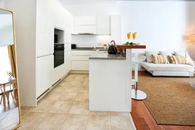 a kitchen and living room with white cabinets at Endless Summer Apartment in Faro