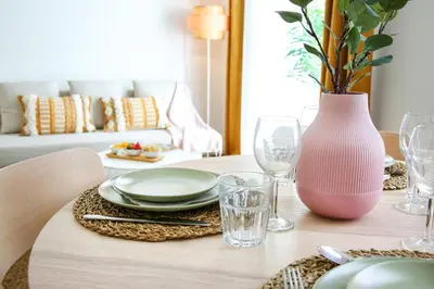 a table with a pink vase and plates and glasses at Endless Summer Apartment in Faro