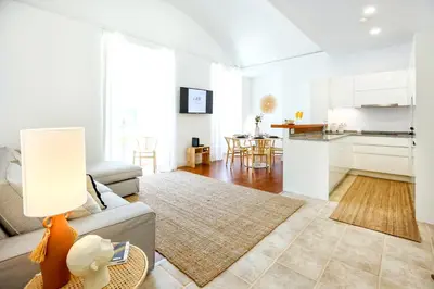 a living room with a couch and a kitchen at Faro Away From Home Apartment in Faro