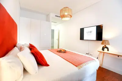a bedroom with a bed with a tv on the wall at Faro Away From Home Apartment in Faro