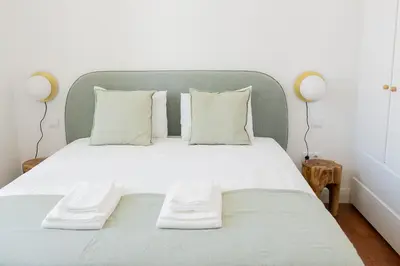 a bedroom with a large bed with white sheets and pillows at President Pais Apartment in Faro