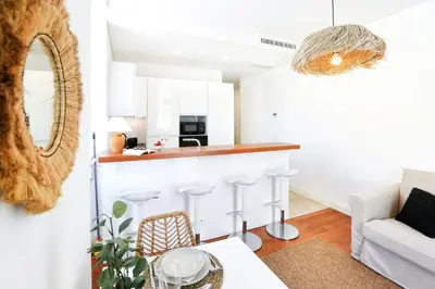 a kitchen and living room with white cabinets and a table at Salty Spot Apartment in Faro