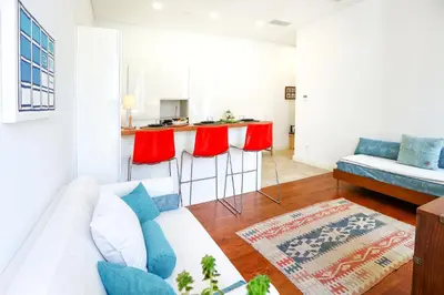a living room with a white couch and red bar stools at Jump Into the Lull Apartment in Faro