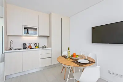 a kitchen with white cabinets and a wooden table at Balaia Senses in Albufeira