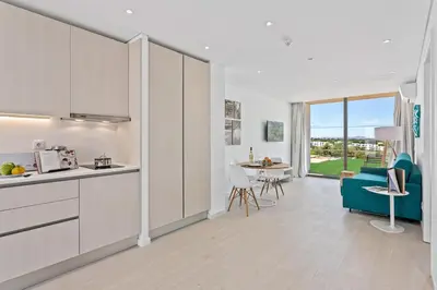 a kitchen with white cabinets and a blue couch and a table at Balaia Senses in Albufeira