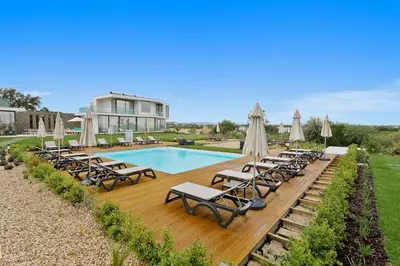 a swimming pool with lounge chairs and umbrellas at Balaia Senses in Albufeira