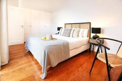 a bedroom with a large bed and a chair at Young Spirit Apartment in Faro