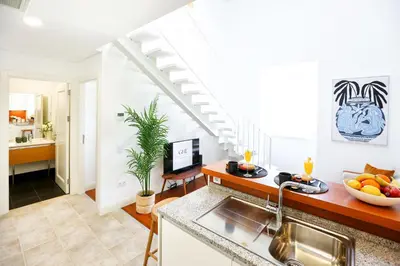 a kitchen with a sink and a living room at Young Spirit Apartment in Faro