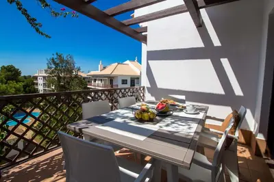 a dining table on a balcony with a view of the water at Apartment Pine View- Falesia Beach By Dalma Portuguesa in Albufeira