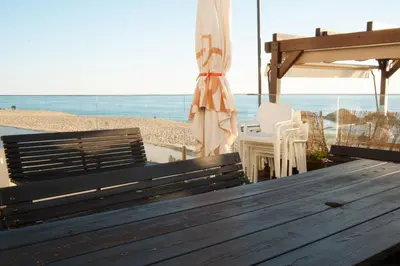 a bench and an umbrella on the beach at Wax Suite By the sea in Faro