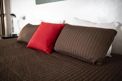 a red pillow sitting on top of a bed at Wax Suite By the sea in Faro