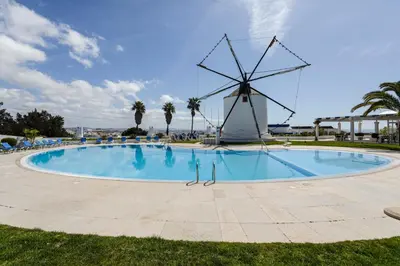 a large pool with a windmill in the background at The Albufeira Concierge - Moinho Sea Views & Pool in Albufeira