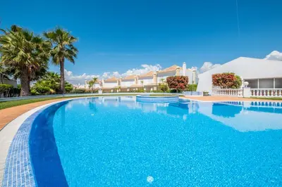 a swimming pool with blue water in front of a house at Villa Jasmin - Galé Bay in Albufeira