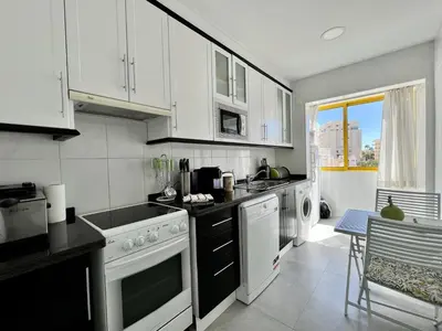 a kitchen with white cabinets and white appliances at Quarteira Stylish 1 by Homing in Quarteira